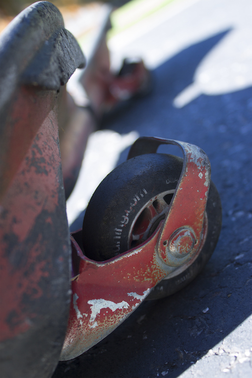 This is a photo of a wheel from a wave board, with chipped red paint.